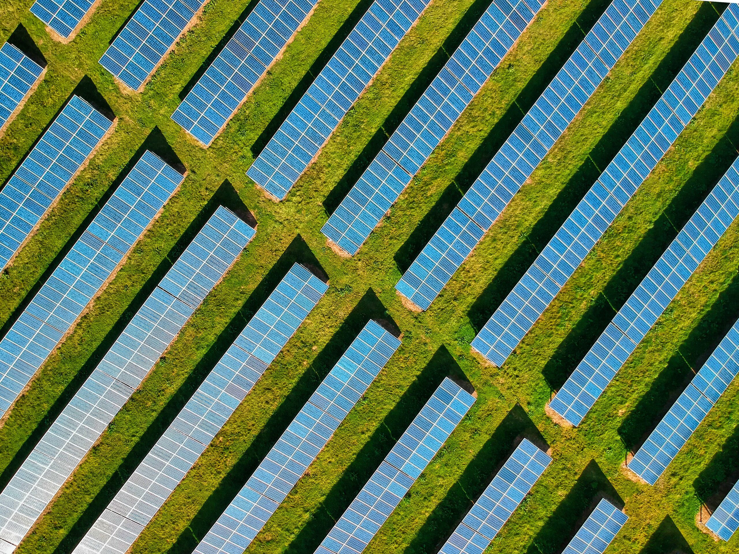 High-angle aerial shot of solar panels in a lush green field, located in Rockbeare, UK.