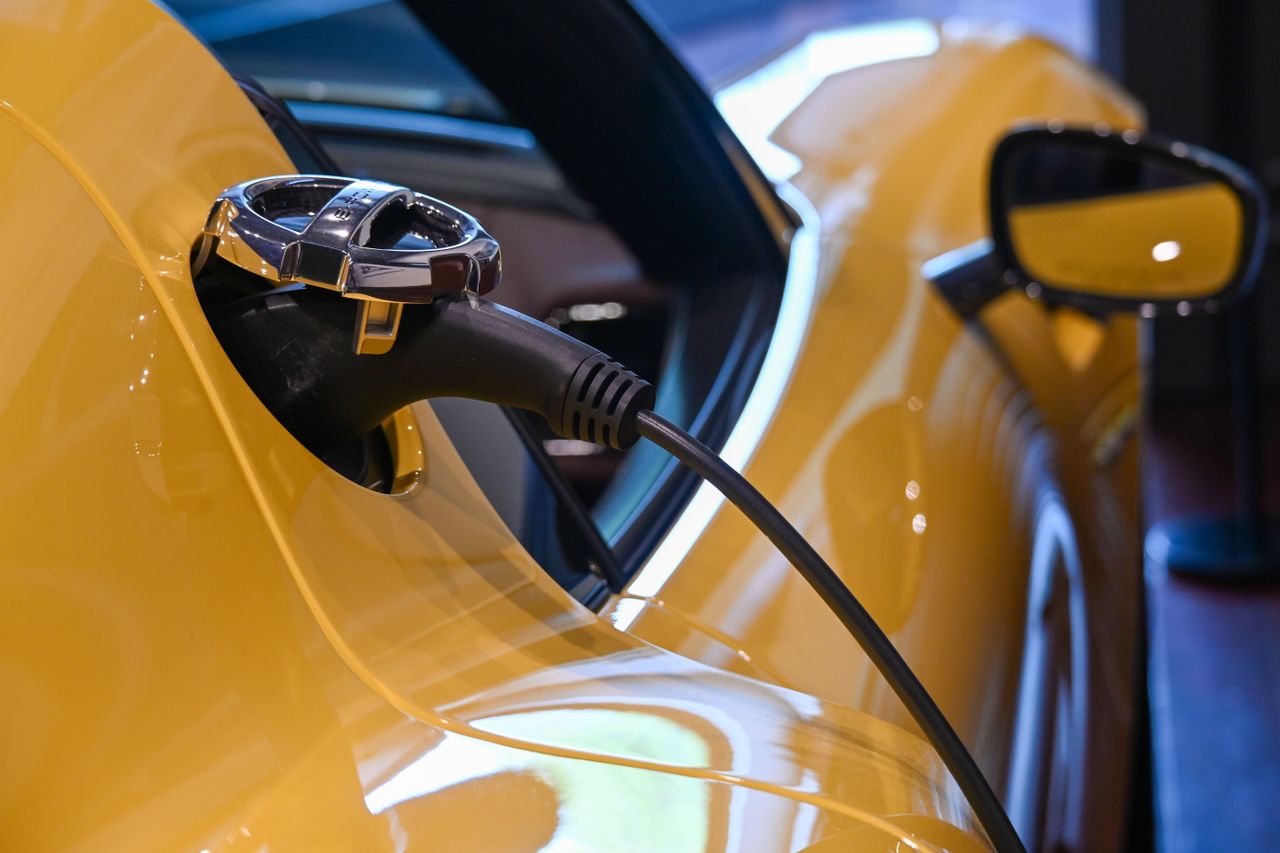 Bonus colonnine domestiche Close-up of a yellow electric vehicle charging with a plugged-in cable indoors.